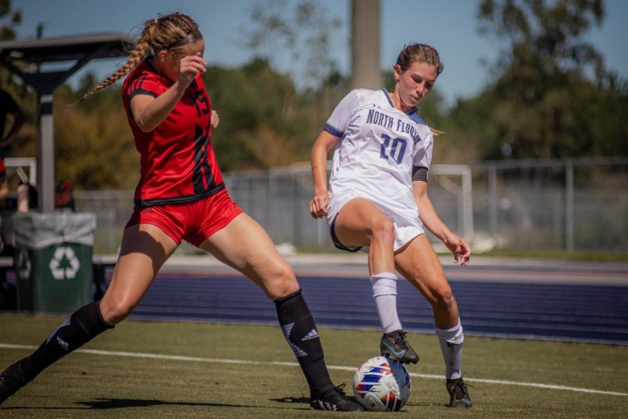 Soccer player protects ball from defender
